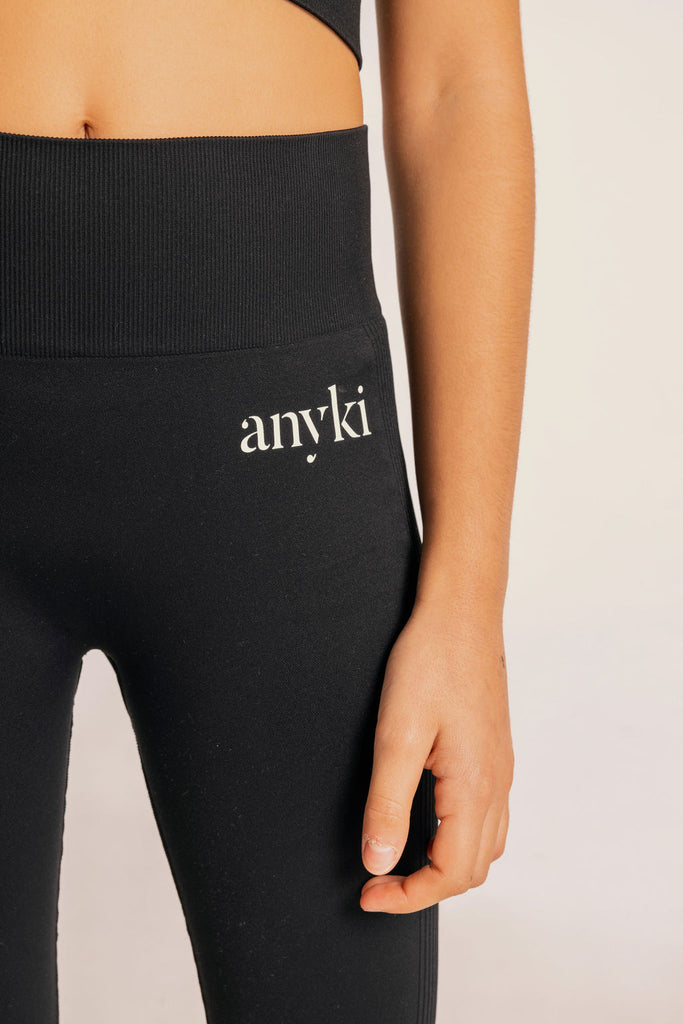 Black seamless leggings with ribbed details for girls with high waist. Available in size 6-14 years old. Designed in Sweden and made of sustainable materials. White logos.