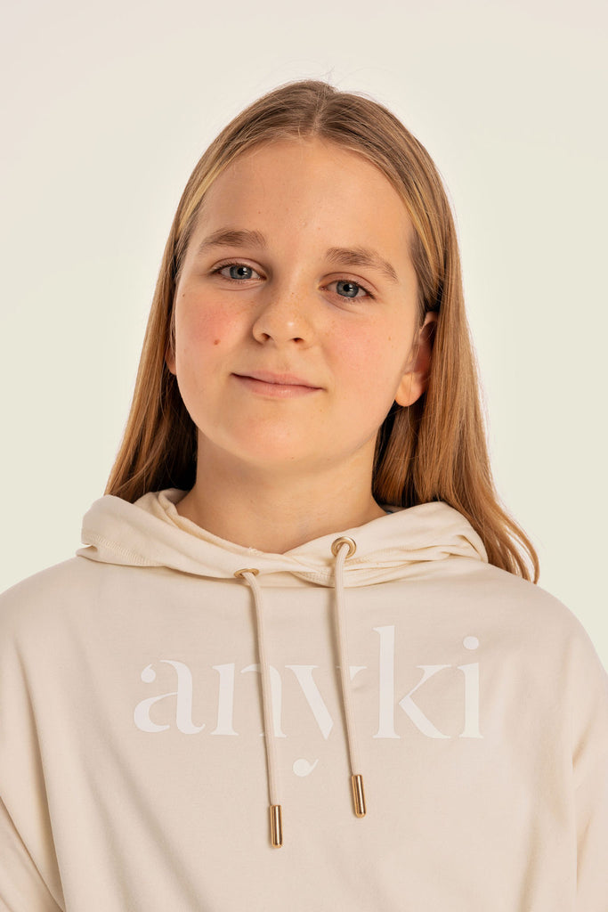 Beige sport hoodie for girls. Available in size 6-14 years old. Seamless material with golden details. Designed in Sweden and made of sustainable materials. 