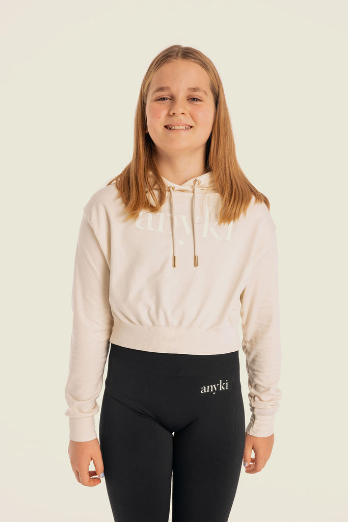 Beige sport hoodie for girls. Available in size 6-14 years old. Seamless material with golden details. Designed in Sweden and made of sustainable materials. 