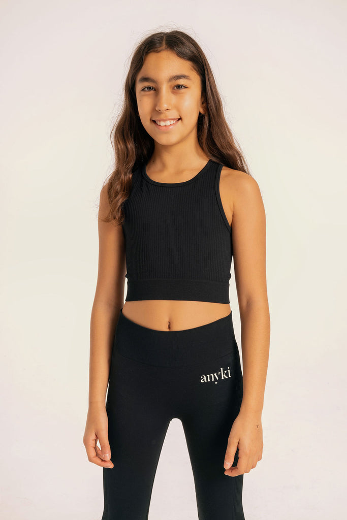 Black seamless top with ribbed details. Available in size 6-14 years old. Designed in Sweden and made of sustainable materials. Perfect for gymnastics or other sports. 